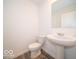 Modern half-bathroom featuring a pedestal sink, toilet, and a decorative mirror at 7509 Big Bend Blvd, Camby, IN 46113
