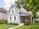 Charming light blue two-story home features a well-maintained lawn and inviting front porch with brick supports at 809 N Temple Ave, Indianapolis, IN 46201