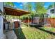 Backyard featuring a trampoline, patio, grilling area, wooden fence, and bright green grass at 8103 Laughlin Dr, Indianapolis, IN 46219