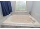 Close-up of a luxurious bathtub with marble surround, tiled accents, and natural light from the window at 8627 Lansdowne Dr, Fishers, IN 46038