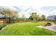 Large grassy backyard with a wood fence, landscaping, and a glimpse of the pond at 905 N Main St, Fortville, IN 46040