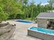 This backyard features a stunning in-ground pool, hot tub, stone pool house, and a spacious patio for outdoor entertaining at 9155 Kerwood Dr, Indianapolis, IN 46240