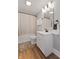 Well-lit bathroom featuring modern vanity, wood-look flooring, and shower with neutral curtain at 921 S State Ave, Indianapolis, IN 46203