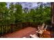 Spacious back deck overlooking a lush forest, complete with comfortable wooden chairs and railings at 9387 Sullivan Pl, Zionsville, IN 46077