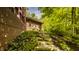 Landscaped backyard featuring stone steps leading up to a brick home surrounded by lush greenery and mature trees at 9387 Sullivan Pl, Zionsville, IN 46077