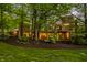 Exterior view of a home at twilight with stone and brick elements, surrounded by lush greenery and mature trees at 9387 Sullivan Pl, Zionsville, IN 46077