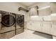 Modern laundry room with stainless steel washer and dryer, white cabinets, and tiled flooring at 9387 Sullivan Pl, Zionsville, IN 46077