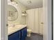 Bathroom featuring blue vanity, round mirror, and blue tiled floors with white shower curtain at 9493 Timber View Dr, Indianapolis, IN 46250