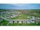 Aerial view of a community with houses surrounding a small lake, featuring mature trees and well-maintained streets at 9823 Pica Dr, Fishers, IN 46040