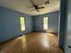 Bedroom with blue walls, two windows, a ceiling fan and light hardwood floors at 9976 W Center St, Anderson, IN 46011