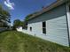 Side view of a light blue house with green grass and a blue sky above at 9976 W Center St, Anderson, IN 46011
