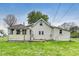 A quaint home with a back porch and sunroom sits on a grassy lot beneath a cloudy sky at 115 S Center St, Maxwell, IN 46154