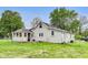 A cozy home with a back porch, sunroom and grassy yard sits under a clear, blue sky at 115 S Center St, Maxwell, IN 46154