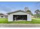 A detached white garage with an open door is situated on a grassy lot with trees at 115 S Center St, Maxwell, IN 46154