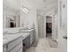 Bright bathroom with double sinks, granite countertops, a shower, and an open doorway to a walk-in closet at 1289 Sunset Blvd, Avon, IN 46123