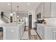 A well-lit kitchen featuring gray cabinets, stainless steel appliances, a spacious island and a pantry door at 1289 Sunset Blvd, Avon, IN 46123