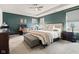 Main bedroom with a tray ceiling, a ceiling fan, a desk and chair, and a comfortable bed with an ottoman at 1289 Sunset Blvd, Avon, IN 46123