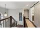 Upstairs hallway featuring hardwood floors, barn door to bathroom, and natural lighting at 13248 Blacktern Way, Carmel, IN 46033
