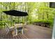 Charming back deck featuring outdoor seating under an umbrella, surrounded by lush greenery and trees at 1334 Legacy Ct, Indianapolis, IN 46234