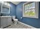 Bathroom showcasing blue walls, patterned tile floors, window, toilet, and vanity with integrated sink at 1601 E Edwards Ave, Indianapolis, IN 46227