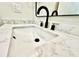 Close-up of a modern bathroom sink with white countertop and stylish black and gold fixtures at 1721 Thaddeus St, Indianapolis, IN 46203