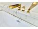 Close-up on a modern bathtub faucet with gold fixtures and marble backsplash at 1721 Thaddeus St, Indianapolis, IN 46203