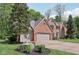 Charming red brick home with a three-car garage, lush greenery, and a beautifully landscaped yard at 2884 Brook Vista Dr, Carmel, IN 46032