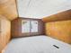 An attic space features wood-paneled walls, textured ceilings, and carpeting with a window at 2908 Fairview St, Anderson, IN 46016