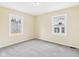 A bright bedroom features neutral walls and carpeting with two windows to allow ample light at 2908 Fairview St, Anderson, IN 46016