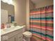 Bright bathroom featuring a shower with a vibrant striped curtain, a toilet, and a modern sink with a mirror at 345 Ehrlich Ln, Westfield, IN 46074