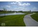 A picturesque pond with a fountain is surrounded by lush green grass and a walking path on a sunny day at 345 Ehrlich Ln, Westfield, IN 46074