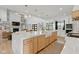 Open kitchen with a large island, farmhouse sink, wood cabinets, and stone fireplace in the adjacent living area at 4078 Besbie Way, Bargersville, IN 46106