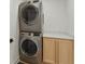 Efficient laundry area with stacked washer and dryer, complemented by a light wood cabinet with sleek countertop at 4078 Besbie Way, Bargersville, IN 46106