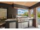 Outdoor kitchen boasts stainless steel appliances, brick accents, a grill, and a bar area overlooking a verdant backyard at 4078 Besbie Way, Bargersville, IN 46106