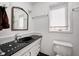 Clean bathroom features a white sink, toilet, mirror, and window for natural light and ventilation at 4302 Kessler Blvd N Dr, Indianapolis, IN 46220