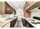 Traditional kitchen featuring wood cabinetry, white appliances, and a charming brick accent wall at 4302 Kessler Blvd N Dr, Indianapolis, IN 46220