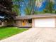 A charming single-story stone home with a bright yellow front door and an attached two car garage at 444 Buffalo Dr, Indianapolis, IN 46217
