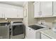 Well-lit laundry room with modern side-by-side washer and dryer and cabinetry at 4732 Ferguson Rd, Indianapolis, IN 46239