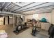 Unfinished basement is partially finished with exercise equipment and painted rafters at 5015 E 70Th E St, Indianapolis, IN 46220
