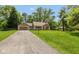 Wide view of a single-story home with an attached garage and a long driveway, surrounded by lush green landscaping at 5015 E 70Th E St, Indianapolis, IN 46220