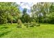 Lush backyard featuring mature trees, a well-manicured lawn, and natural landscaping at 5721 Daphne Dr, Indianapolis, IN 46278