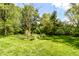 Spacious backyard with mature trees, green lawn, and a sunny blue sky overhead at 5721 Daphne Dr, Indianapolis, IN 46278