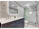 Bathroom featuring a gray-tiled shower, double vanity, and large mirror with integrated lighting at 5811 King Ave, Indianapolis, IN 46228