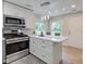 Updated kitchen features white cabinets, stainless steel appliances, and views of the backyard at 5811 King Ave, Indianapolis, IN 46228