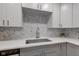 Gray and white kitchen featuring a stainless steel sink, modern faucet, and herringbone backsplash at 5811 King Ave, Indianapolis, IN 46228