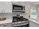 Updated stainless steel gas range with microwave, herringbone backsplash, and light countertop at 5811 King Ave, Indianapolis, IN 46228