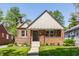 Charming brick home featuring a symmetrical design, covered porch, manicured lawn, and classic architectural details at 5912 Evanston Ave, Indianapolis, IN 46220