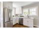 Bright kitchen features stainless steel refrigerator and dishwasher, white cabinetry, and hardwood floors at 5912 Evanston Ave, Indianapolis, IN 46220