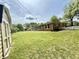 Large backyard showing grass, shed and brick home exterior with white trim, a white fence and green trees at 6335 Linden Dr, Indianapolis, IN 46227