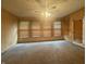 Spacious living room with wood-look walls, gray carpet, and natural light streaming through the many windows at 6335 Linden Dr, Indianapolis, IN 46227
